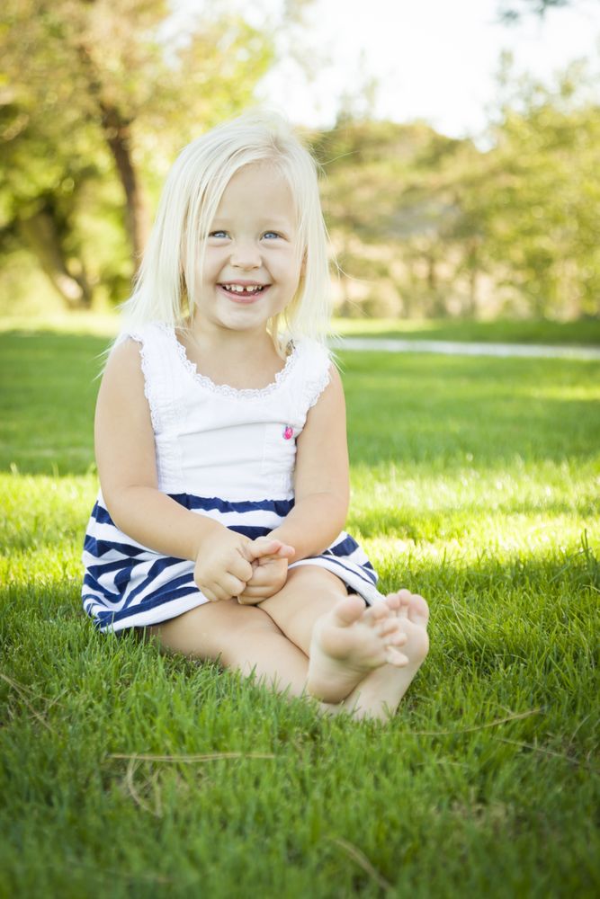 Cute Little Girl Sitting and Laughing in the Grass
