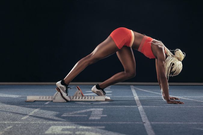 Female athlete taking position on her marks to start off the run