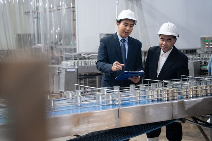 A businessman inspecting canned fish on conveyor belt at the factory