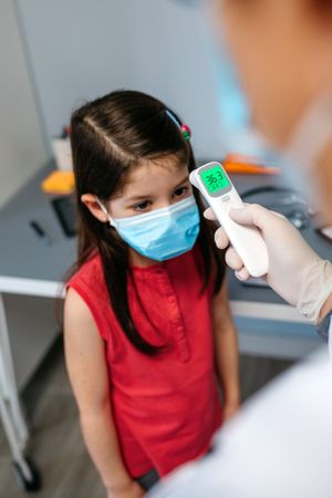Girl without fever whose temperature is taken by her doctor