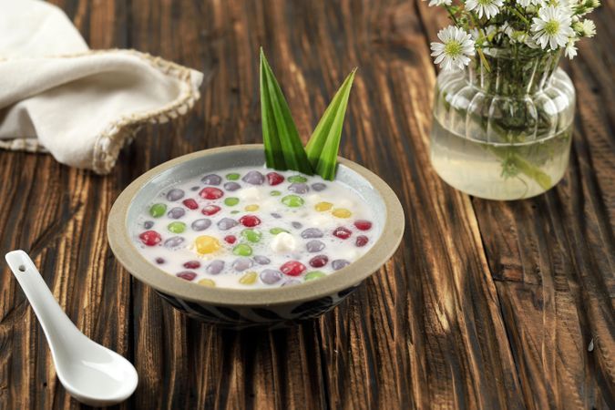 Thai dessert of colorful rice balls in sweet coconut milk on wooden table