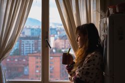 Woman enjoying hot beverage near fridge