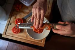 Unrecognizable cook grating red tomato