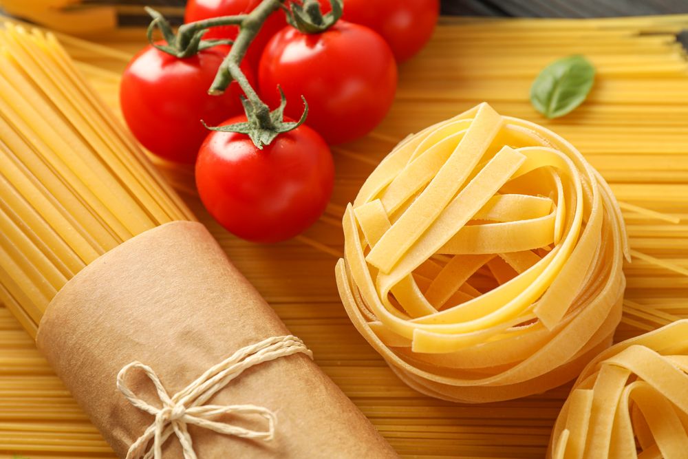 Composition with pasta, tomatoes and basil on wooden background, closeup