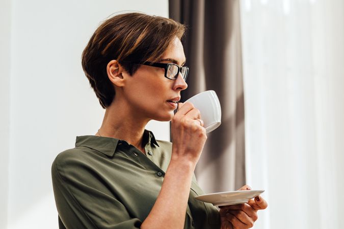 Woman with short hair and glasses with a ceramic cup and saucer
