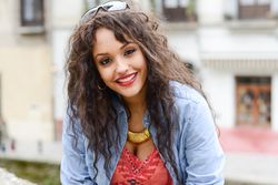 Smiling female with curly hair standing on balcony outside