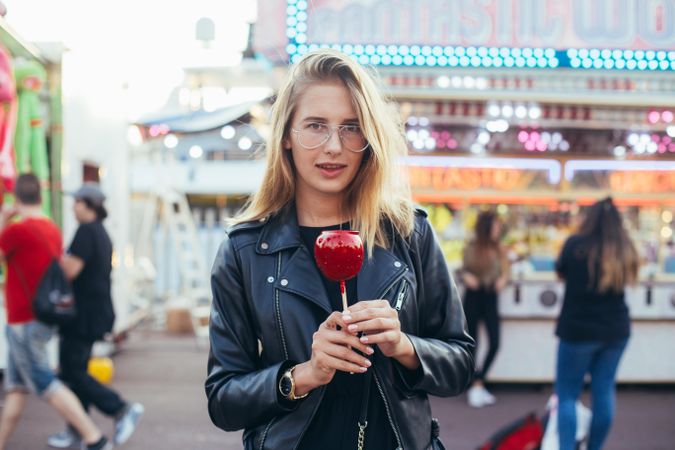 Stylish woman with an incredulous expression with a candied apple