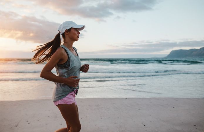 Fit young woman jogging at the beach in morning