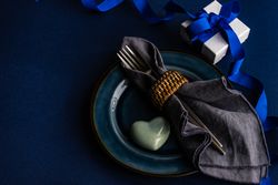 Valentine day table setting with blue plate and heart decoration and present with blue ribbon
