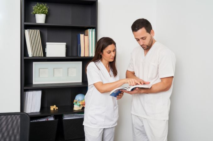 two physiotherapists looking for information in a book