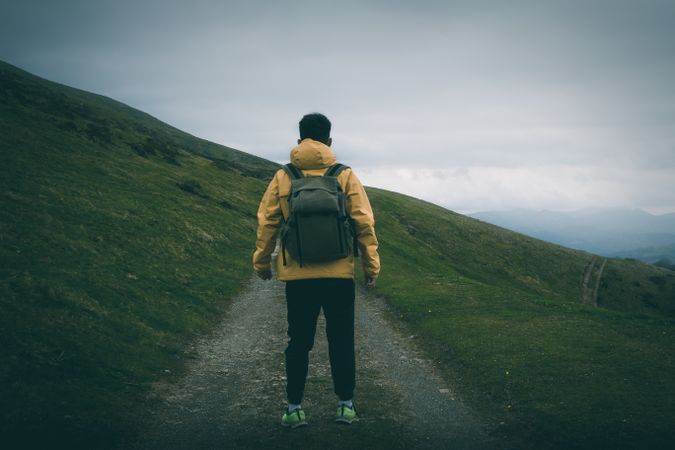 Anonymous traveler standing on road on hillside