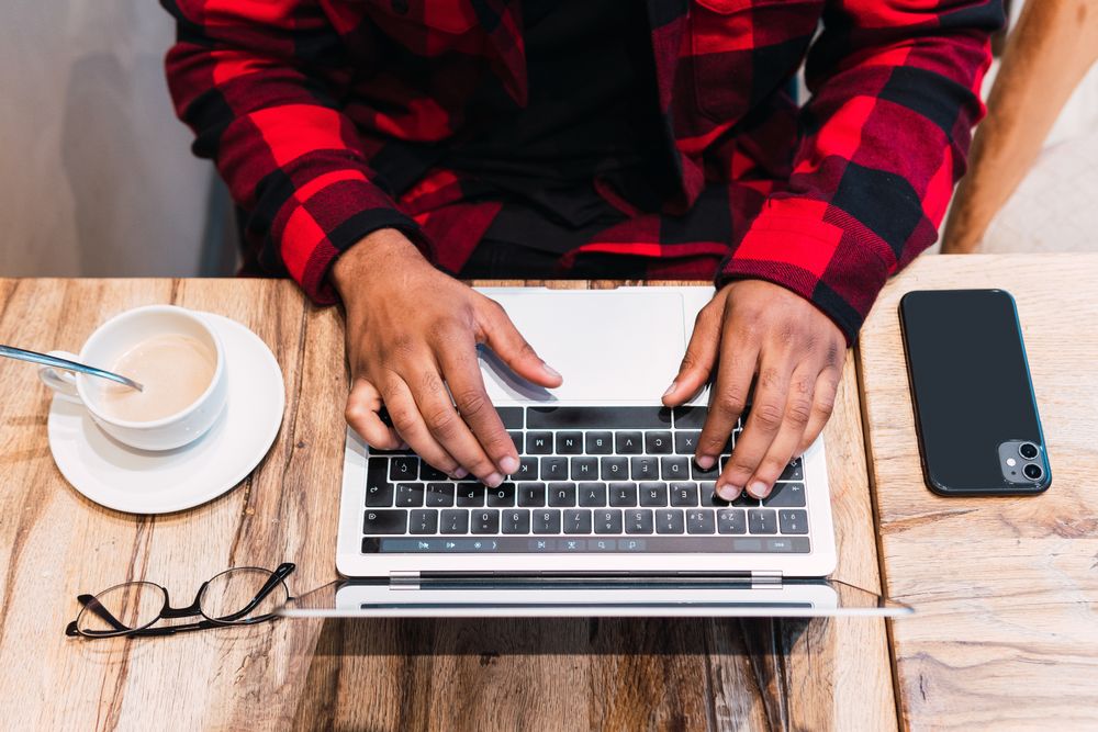 Anonymous Black man working on laptop in cafe
