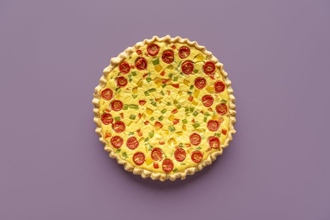 Vegetable quiche top view isolated on a purple background
