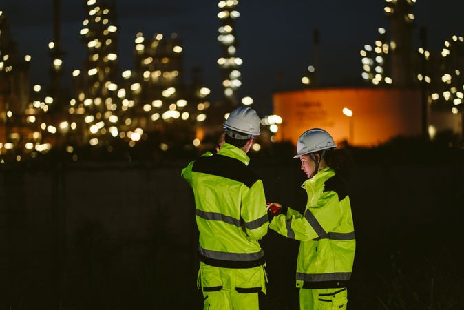 Back view of engineer worker watching work monitor on laptop at refinery factory