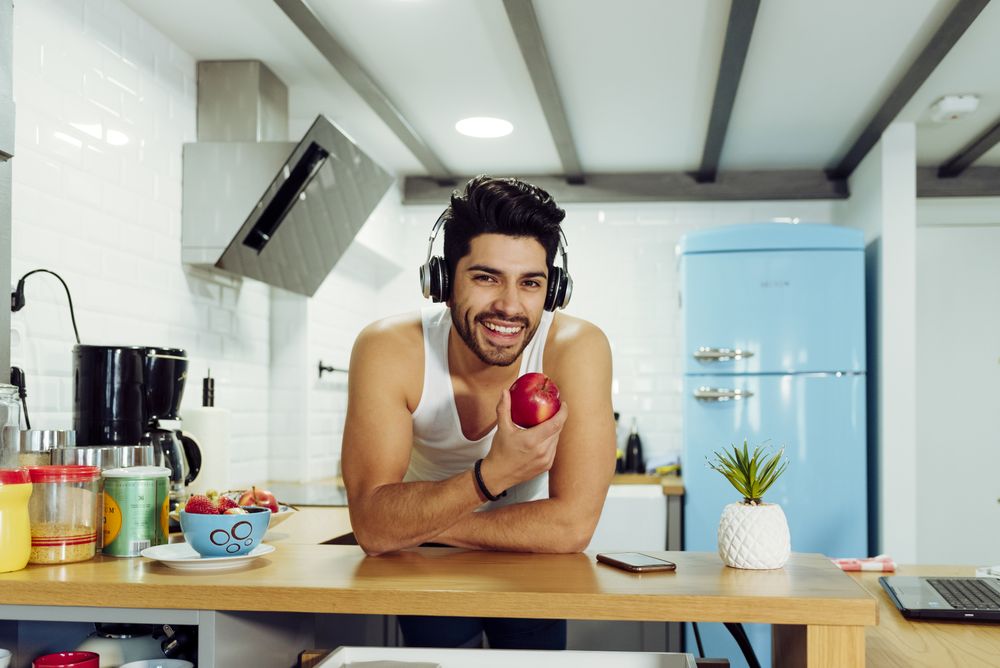 Young happy man in headphones holding apple