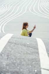 Modern relaxed woman on marked road and browsing smartphone