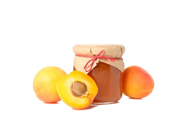 Glass jar with apricot jam and ingredients isolated on blank background