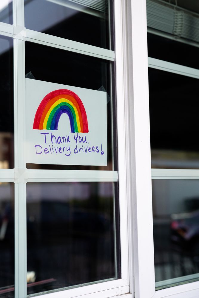 Handwritten sign taped to home window with panes thanking delivery drivers during lockdown