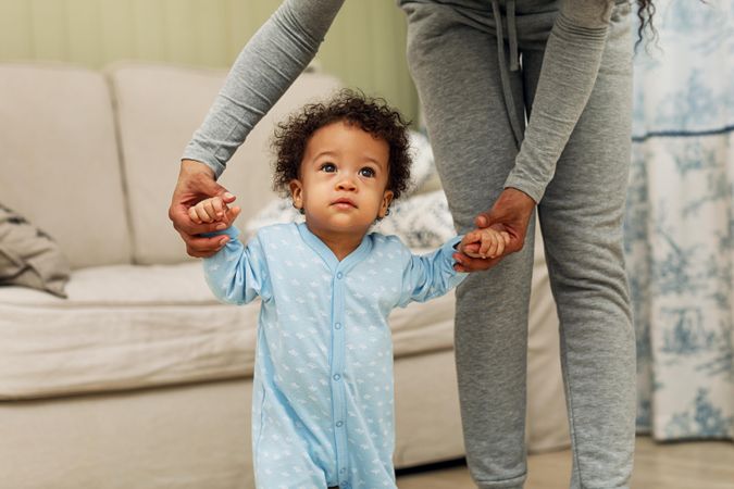 Toddler standing up with mother holding his hands