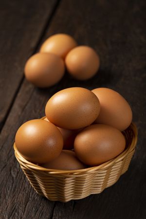 Basket with brown chicken eggs goes up the table.