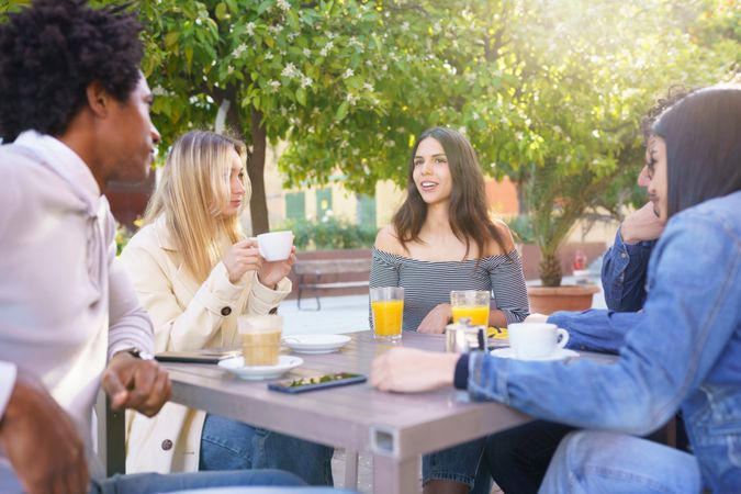 Multi-ethnic friends sitting outside with drinks