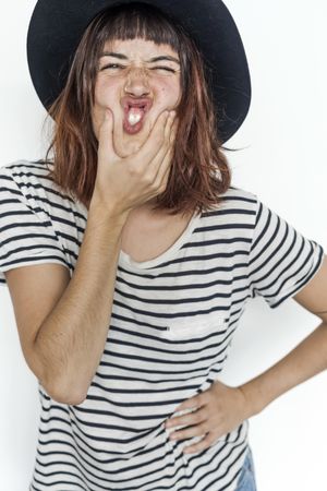 Female in striped shirt and felt hat holding mouth pursing lips
