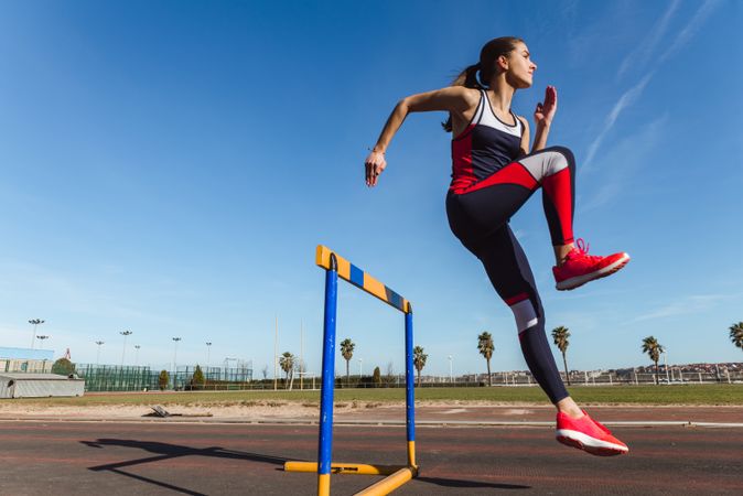 Female athlete hurdling on stadium