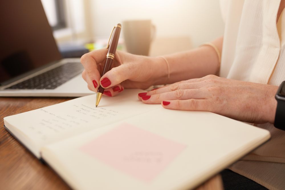 Close up image of woman writing notes in her notebook