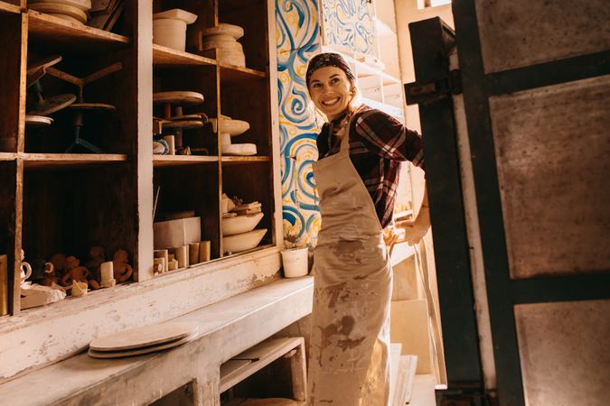 Female potter in pottery workshop adjusting her apron