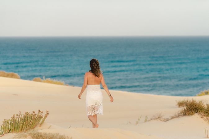 Active woman in white shorts walking sandy beach