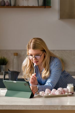 Woman working on tablet in kitchen with breakfast