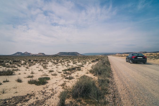 Car driving on empty road along desert