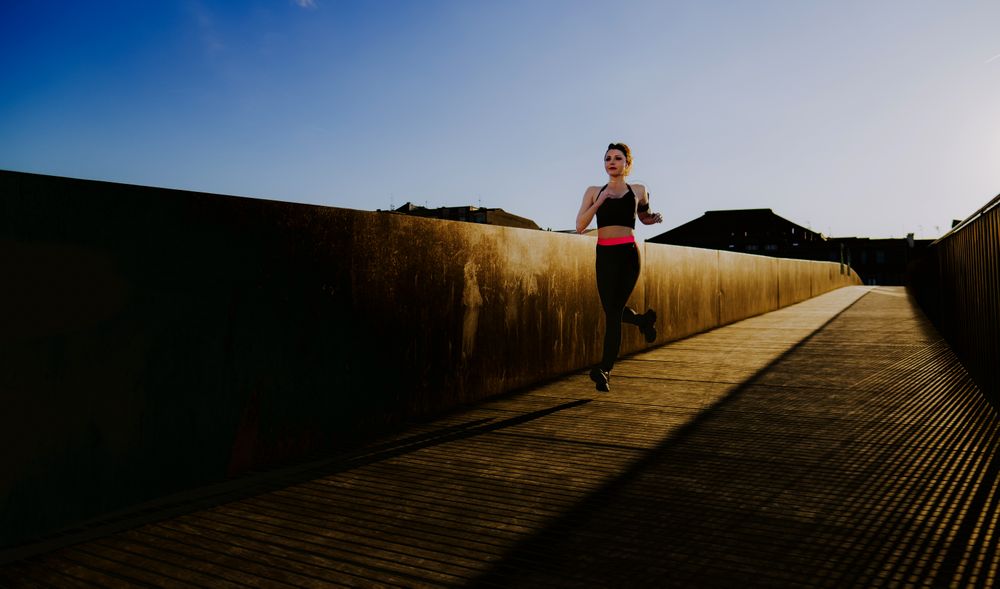 Woman running on walkway in sunny day with blue sky