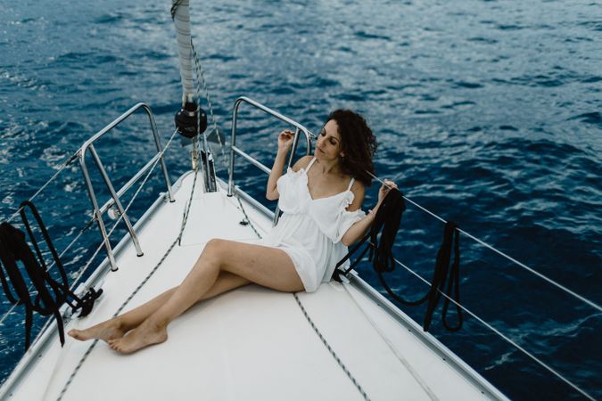 Barefoot bride resting on yacht bow
