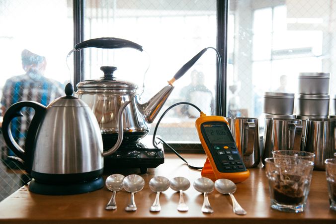 Kettle, thermometer, spoons, glasses and brothers on cafe counter