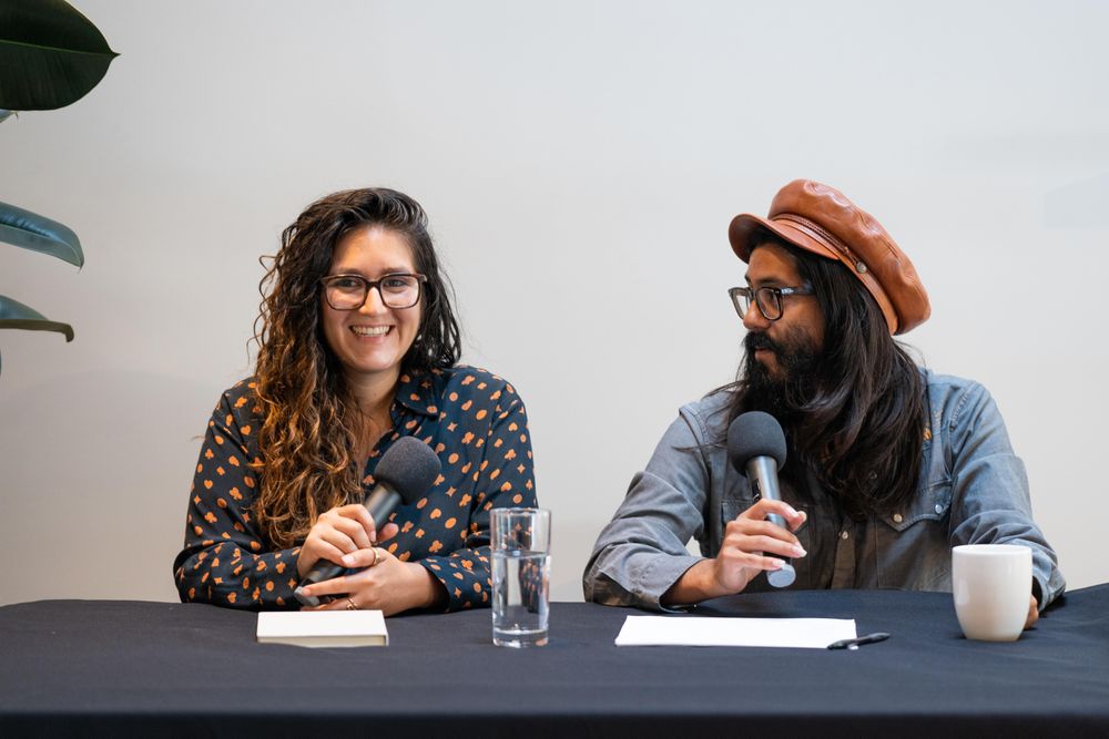 Two people at a table giving a talk