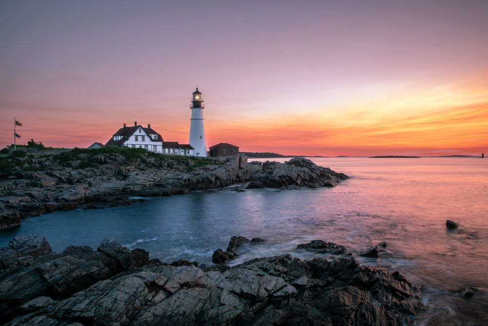 Lighthouse near small house during golden hour