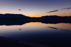 Sundown sky over mountains and calm water