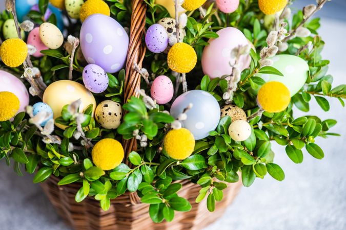 Close up of pastel Easter eggs & flowers in decorative basket