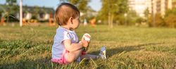 Happy baby girl playing sitting on a grass park