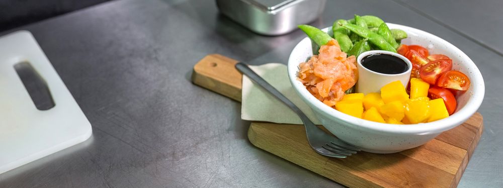 Banner of salmon poke bowl served over wooden board on restaurant kitchen. Healthy food concept.