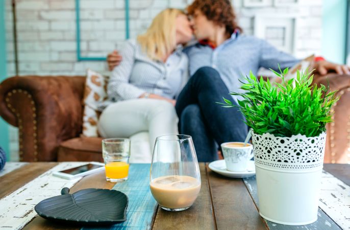 Drinks on a coffee table with a couple kissing