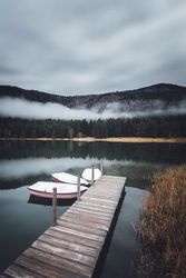 Three dinghies near brown wooden dock on lake