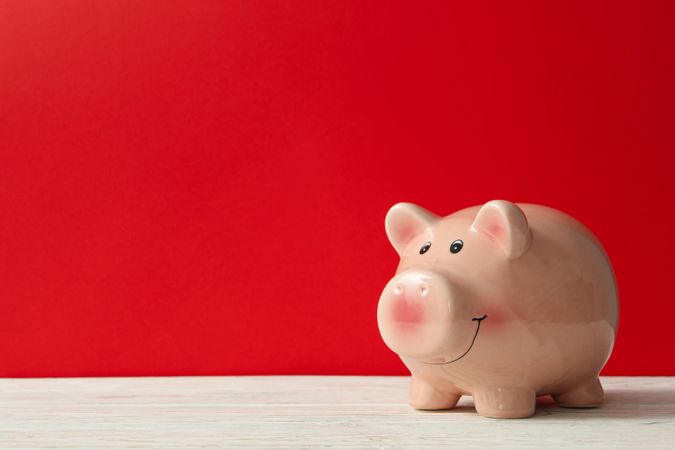 Piggy bank on red background, space for text