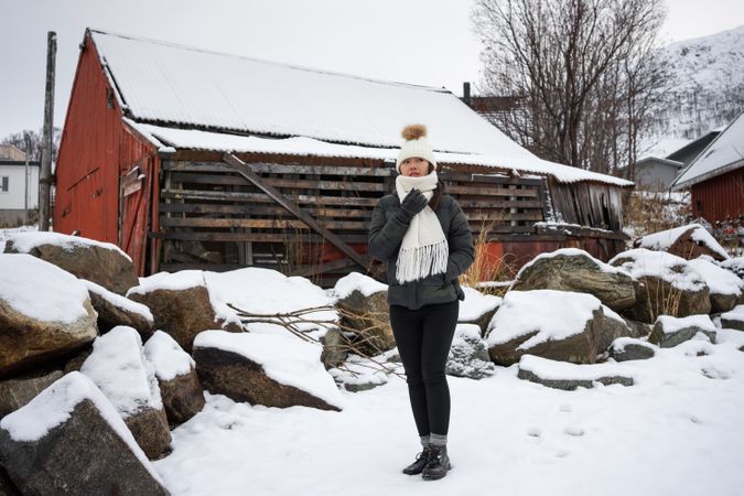 Solitary woman in front of red house in snowy landscape