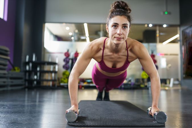 Muscular woman doing planks while holding weights