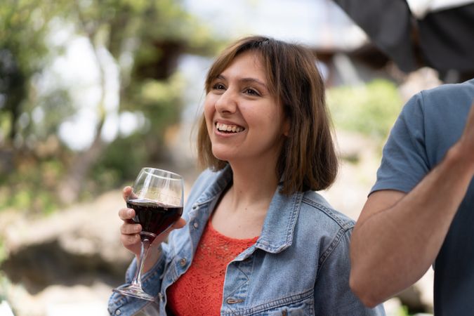 Smiling woman taking a sip from a glass of red wine outside