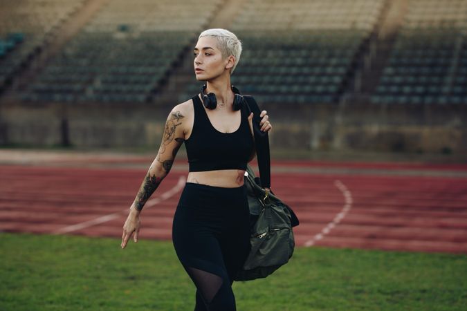 Female runner walking in a track and field stadium carrying her bag