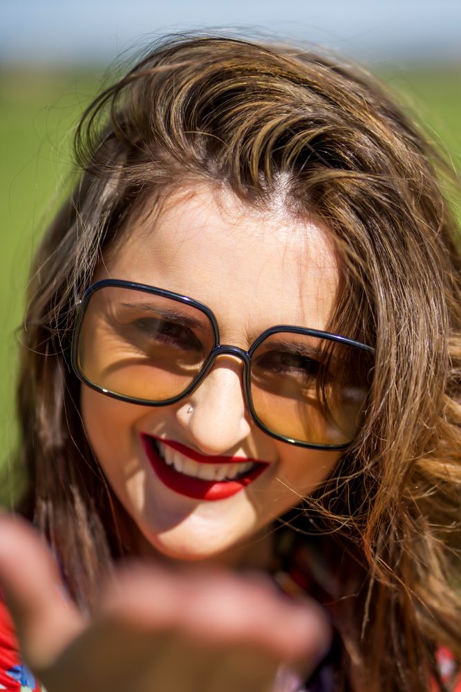 Cheerful woman in sunglasses looking at camera on sunny day