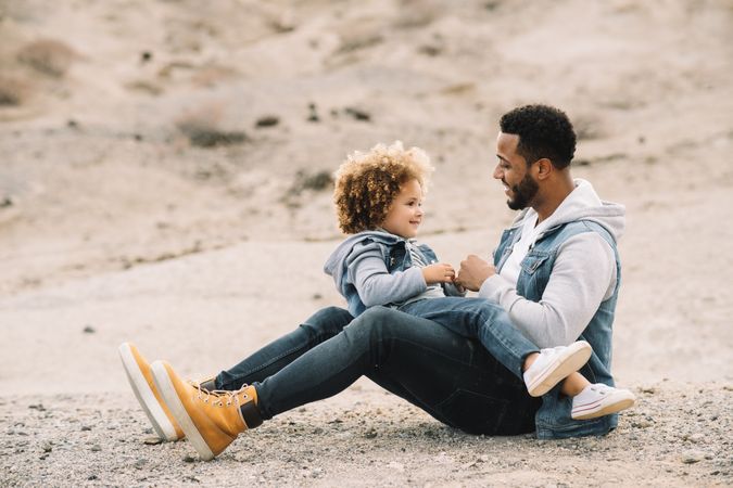 Black father playing with child on ground